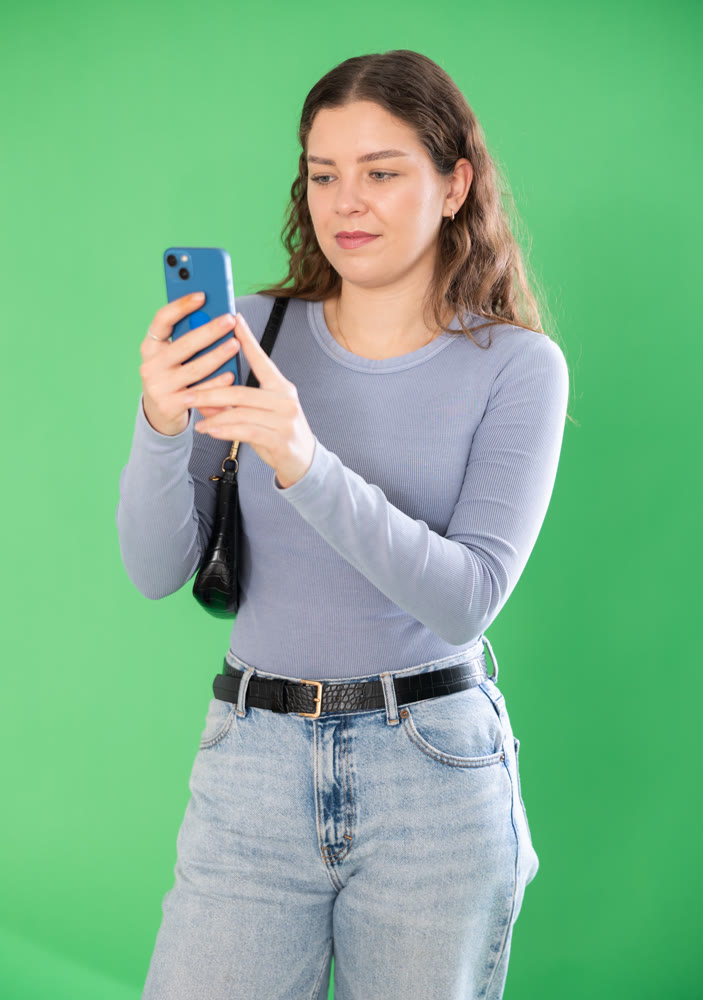 Happy girl scans QR code or takes photo with a smartphone. Green background. Chroma key compositing