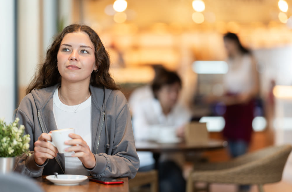 Girl whiles away time and waits for meeting in chain cafe