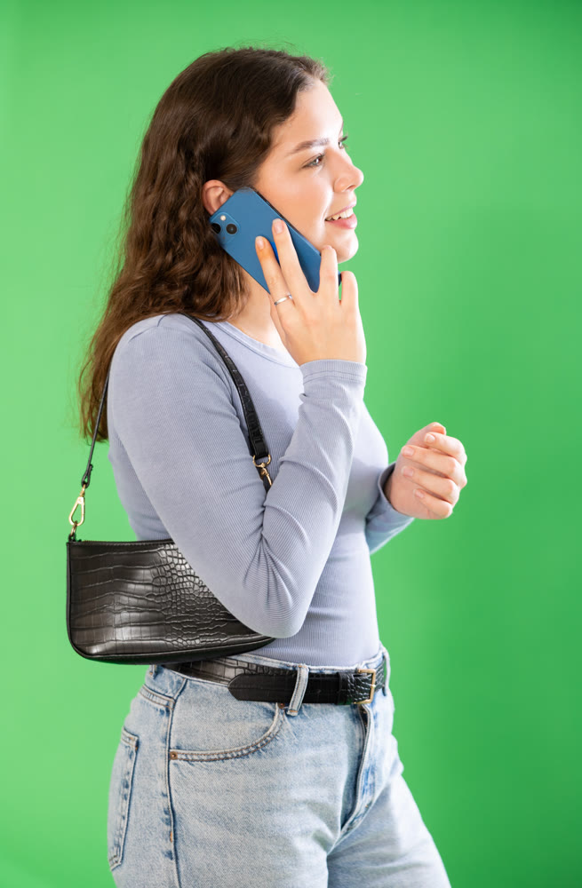 Young woman talking on mobile phone in front of green screen