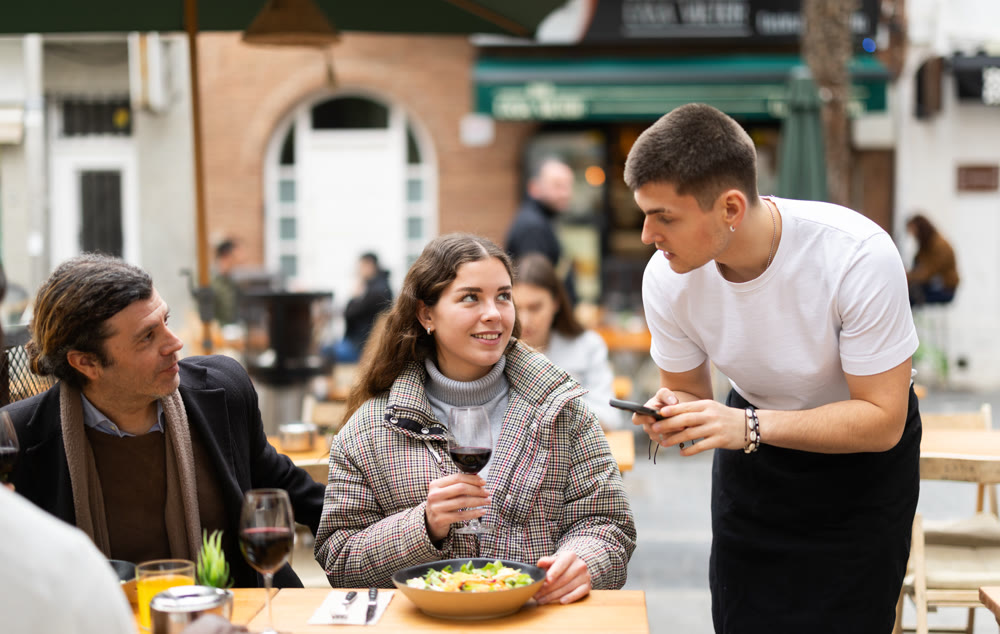 Couple husband and wife ordering from boyfriend waiter in restaurant