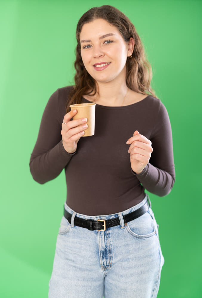 Chroma key compositing. Pretty girl drinking coffee against green chroma key background