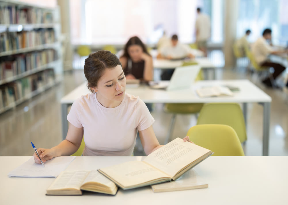 Female student sitting at table and writing