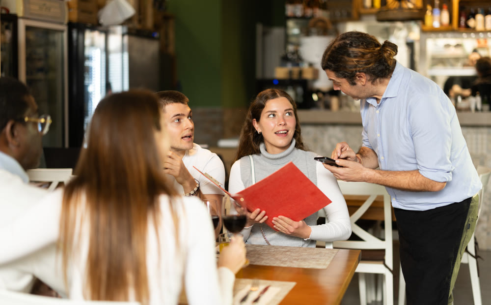 Waiter takes an order from a woman and a group of friends