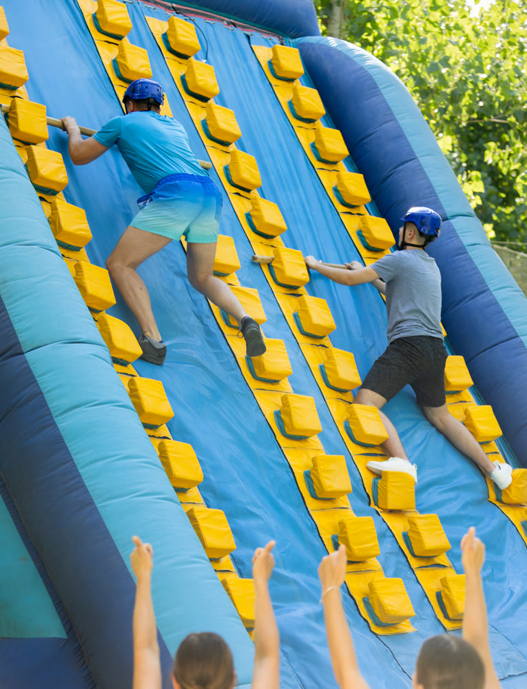 Two men climbing on inflatable castle with wooden sticks