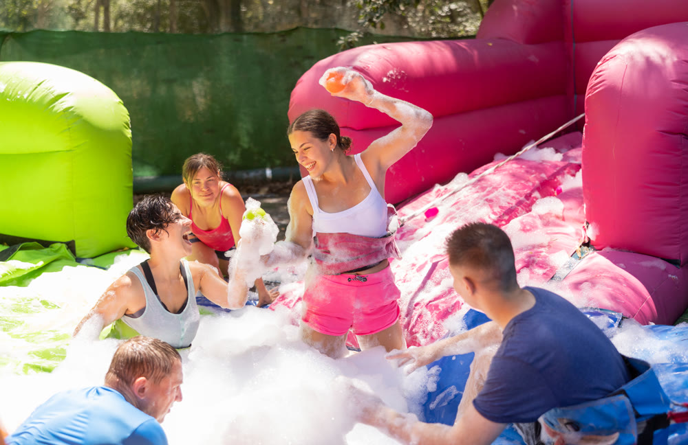 Positive men and women playing interesting game in bubble pool