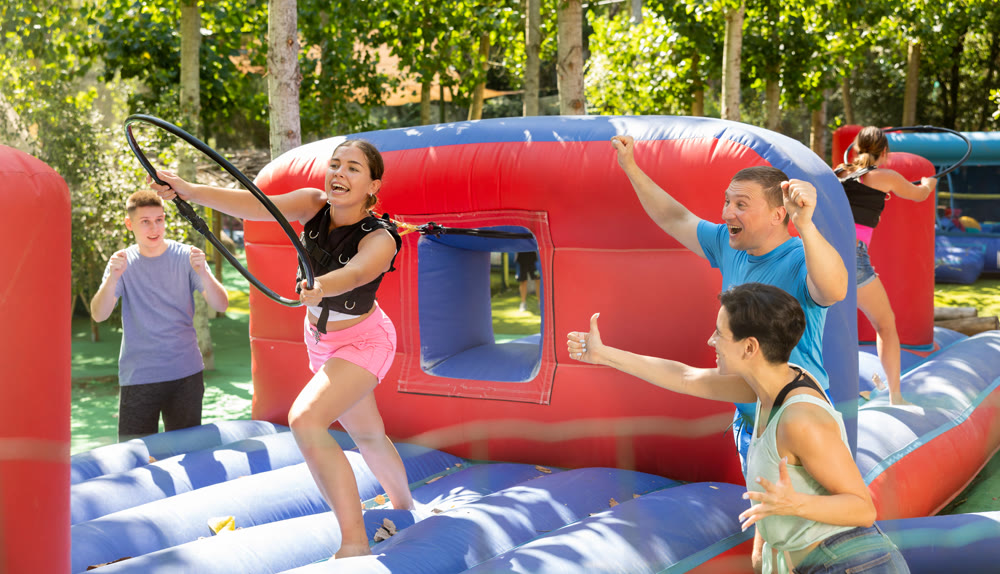 Happy young woman competing with friends in collect hoops on inflatable arena