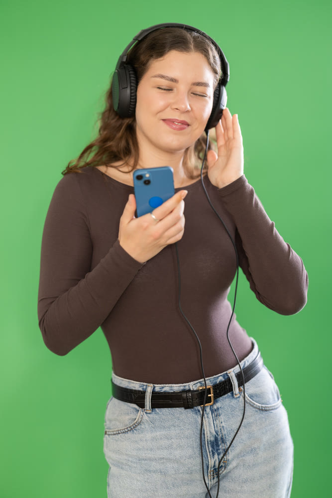 Girl listens to music using wired headphones and mobile phone