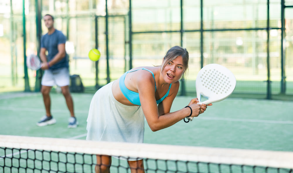 Young woman in skirt playing padel tennis on court
