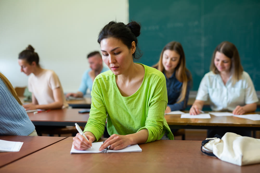Woman university student writing in classroom