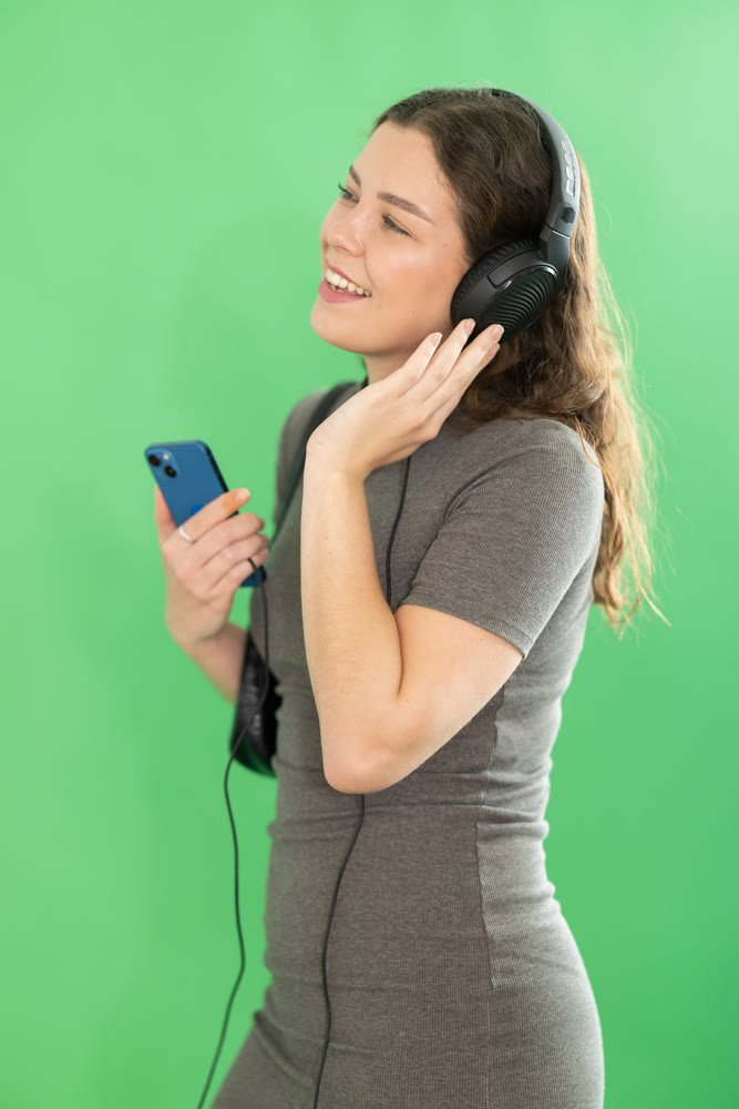 Girl listens to music using wired headphones and mobile phone