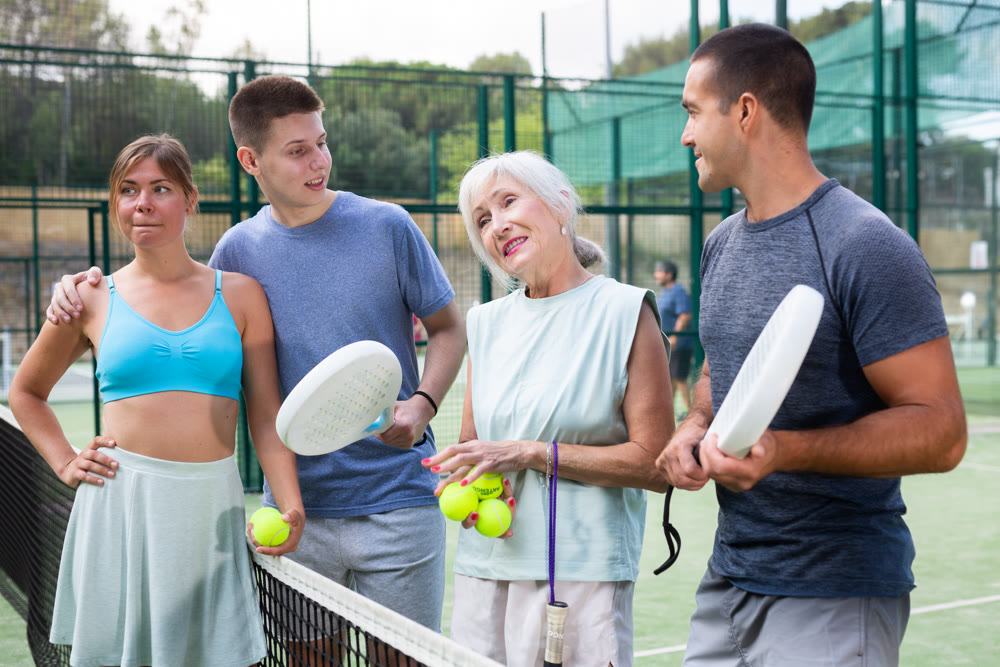 Different aged men and women talking after padel tennis match