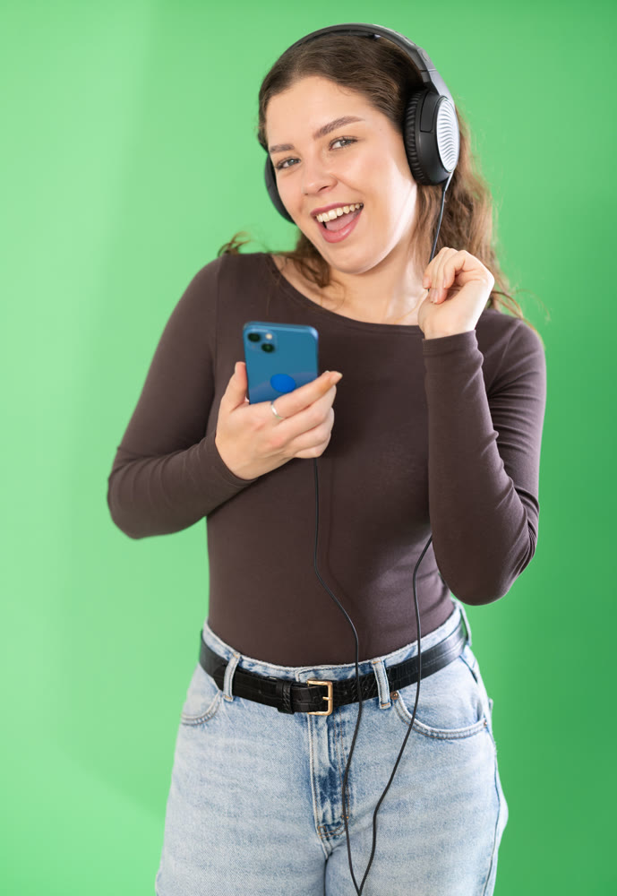 Girl listens to music using wired headphones and mobile phone
