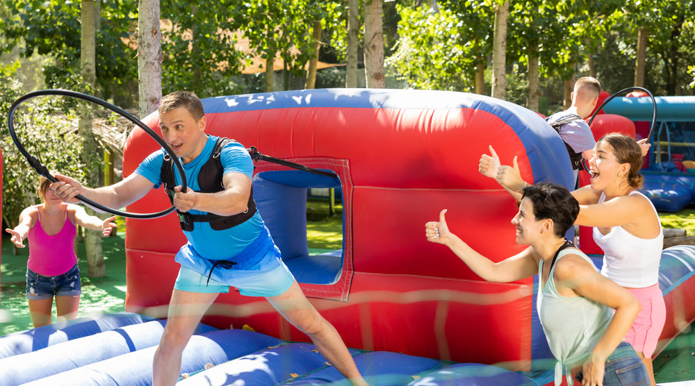 Man playing tug of war game with hoop on playground in amusement park
