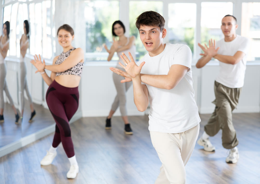 Guy with team of young like-minded people learn to dance modern dances