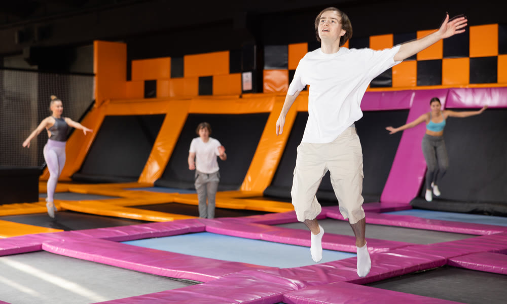 Young guy trains jumping in trampoline center