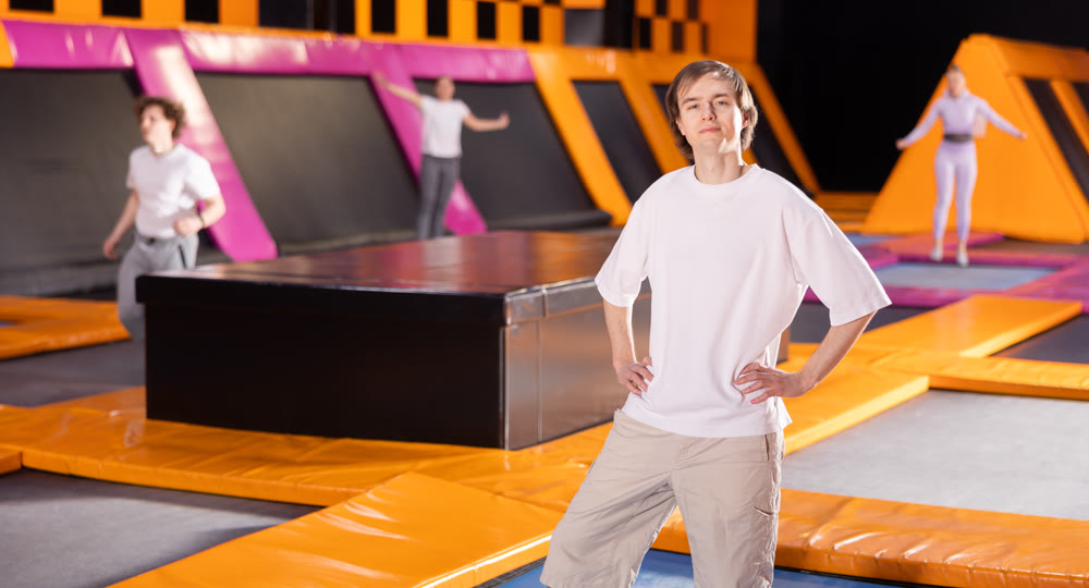 Portrait of positive young man posing on trampolines during active weekend free time in game club