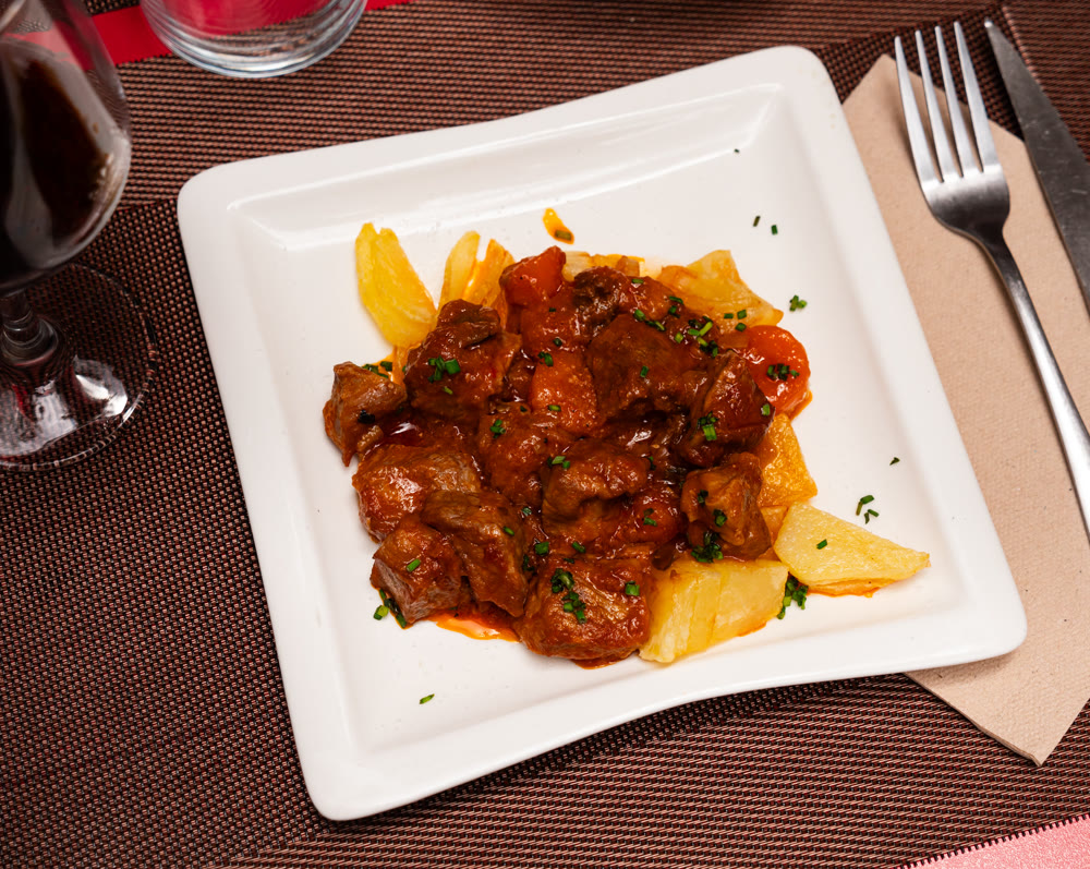 Stewed veal in sauce on a plate with vegetables