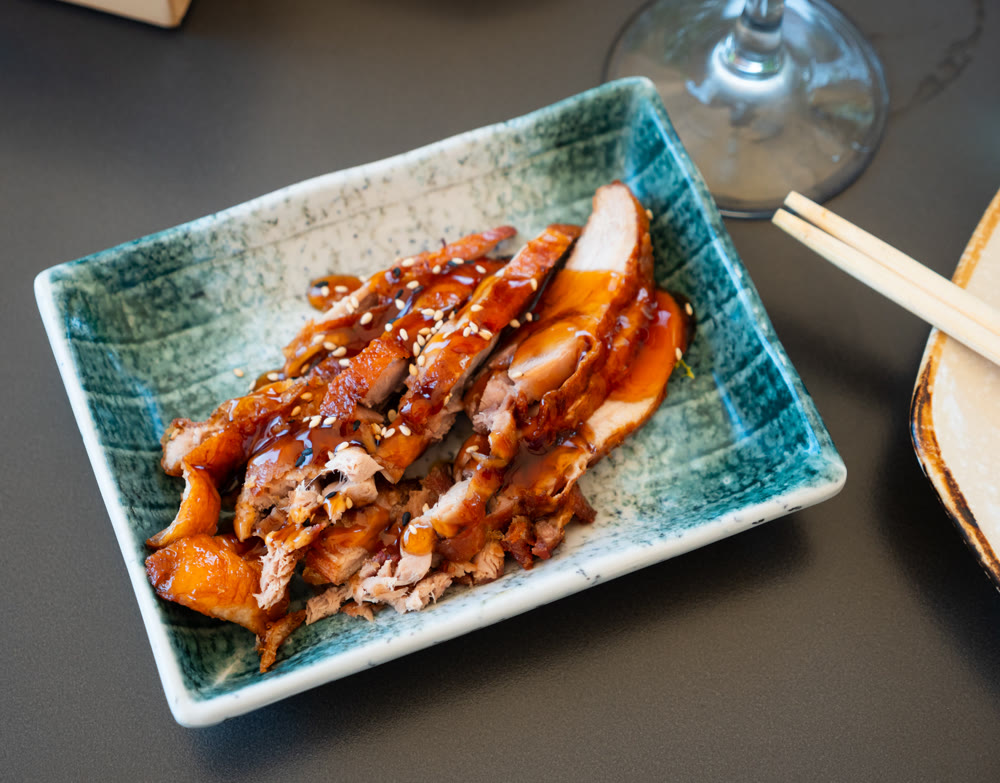 Appetizing pieces of baked duck breast are served with spicy sauce and decorated with white sesame seeds