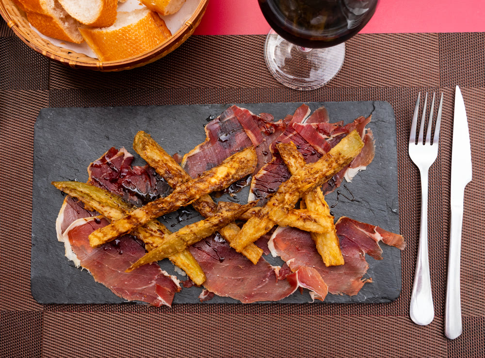 Warm baked appetizer made of slices of pork bacon and pieces of eggplant