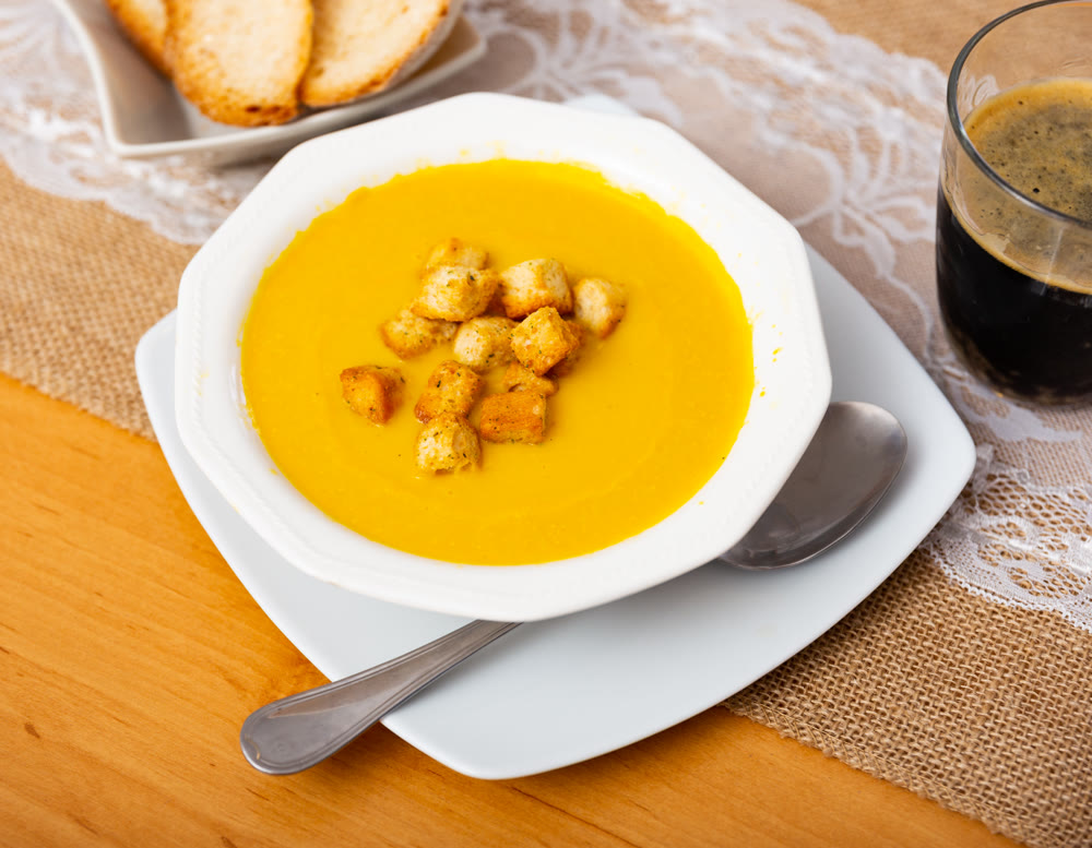 Plate is filled with homogeneous cream soup, dish made from seasonal vegetables and zucchini