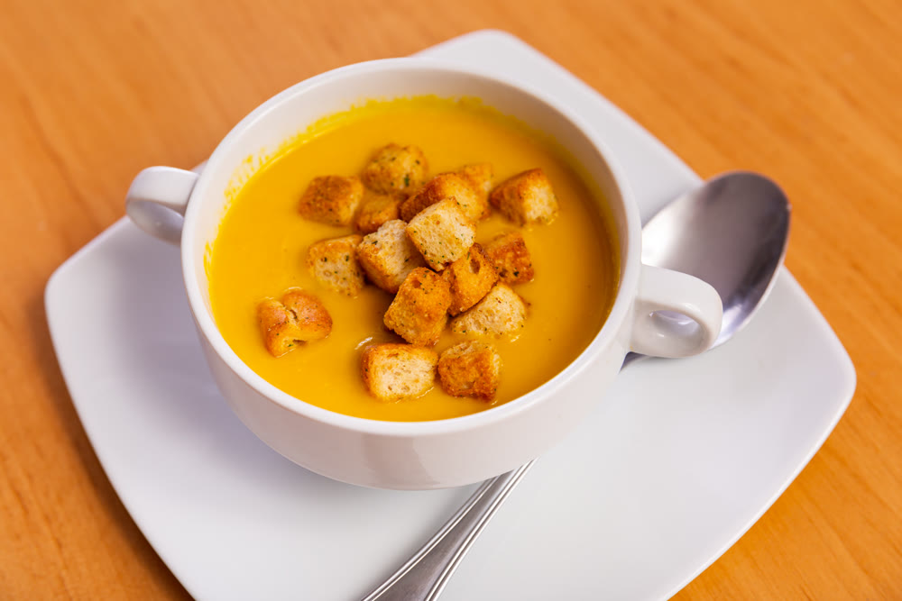 Plate is filled with homogeneous cream soup, dish made from seasonal vegetables and zucchini