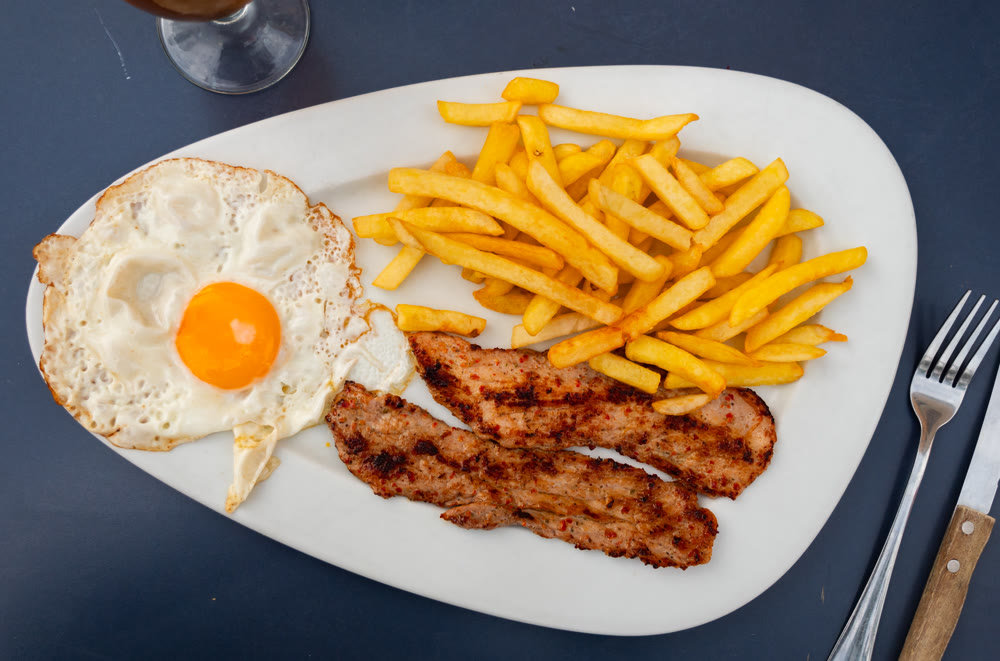 Fried egg and pieces of potato are complemented by butifarra sausage