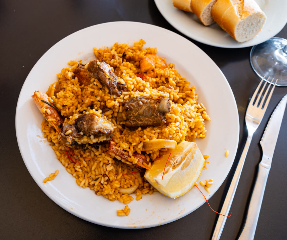 Seafood and meat paella served with fresh lemon
