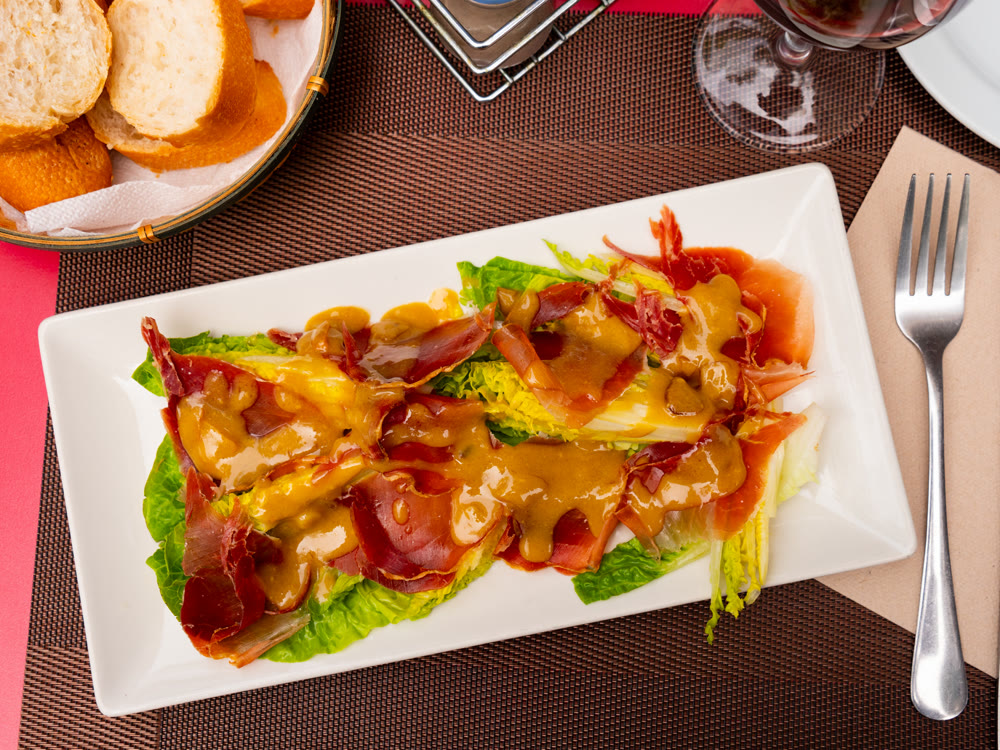 Pork bacon ham slices are baked with young, crisp cogollos lechuga hearts and seasoned with mustard sauce.