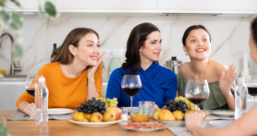 Girlfriends chatting and drinking wine in kitchen