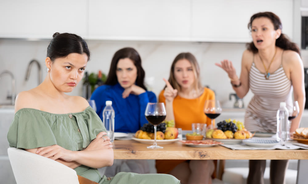 Friends quarrel at party. Upset woman listens to screams and indignation of her girlfriends