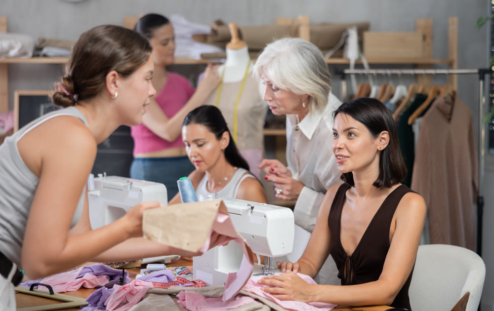 In sewing class young woman working on machine and discussing pattern