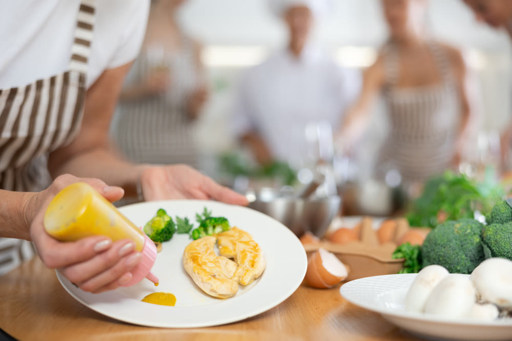 Woman pouring sauce into dish at master class