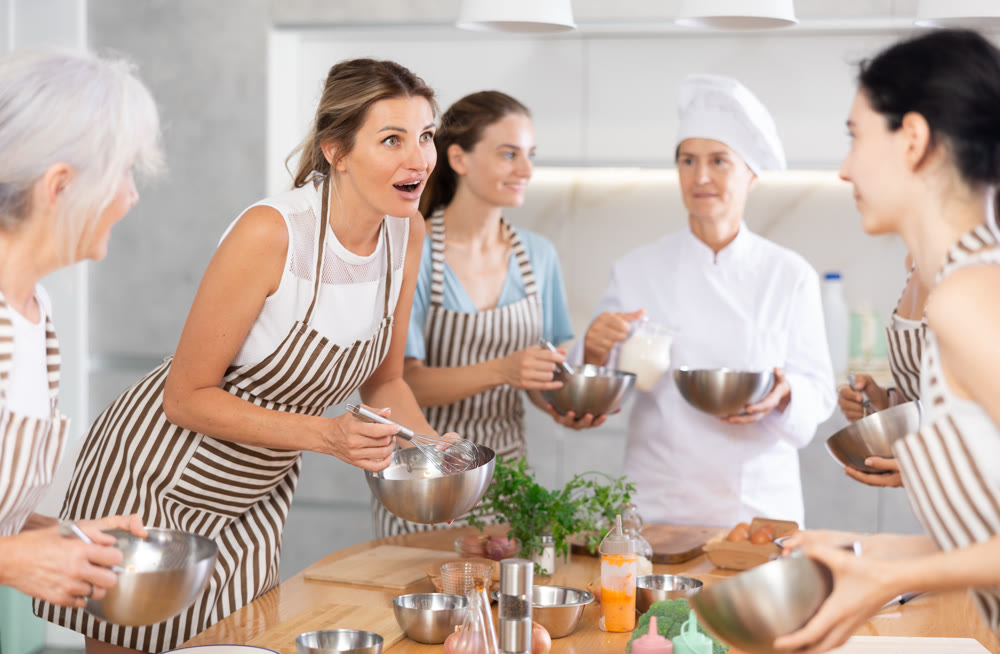 Young female visitor has nice conversation with person facing buddy vis-a-vis at culinary courses