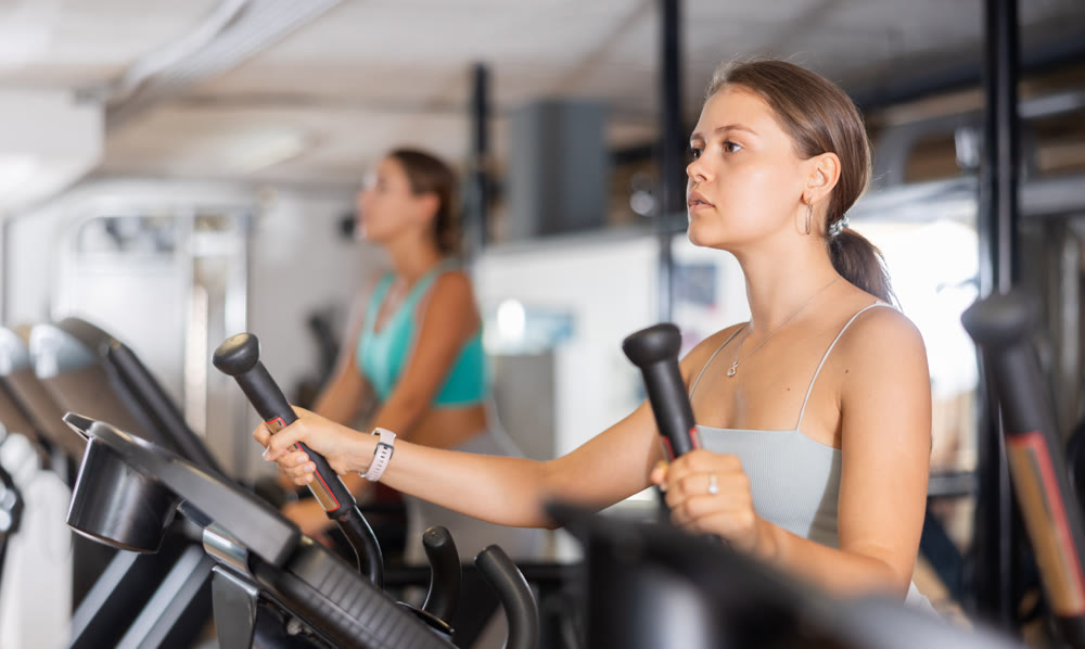 Young woman working out on elliptical machine