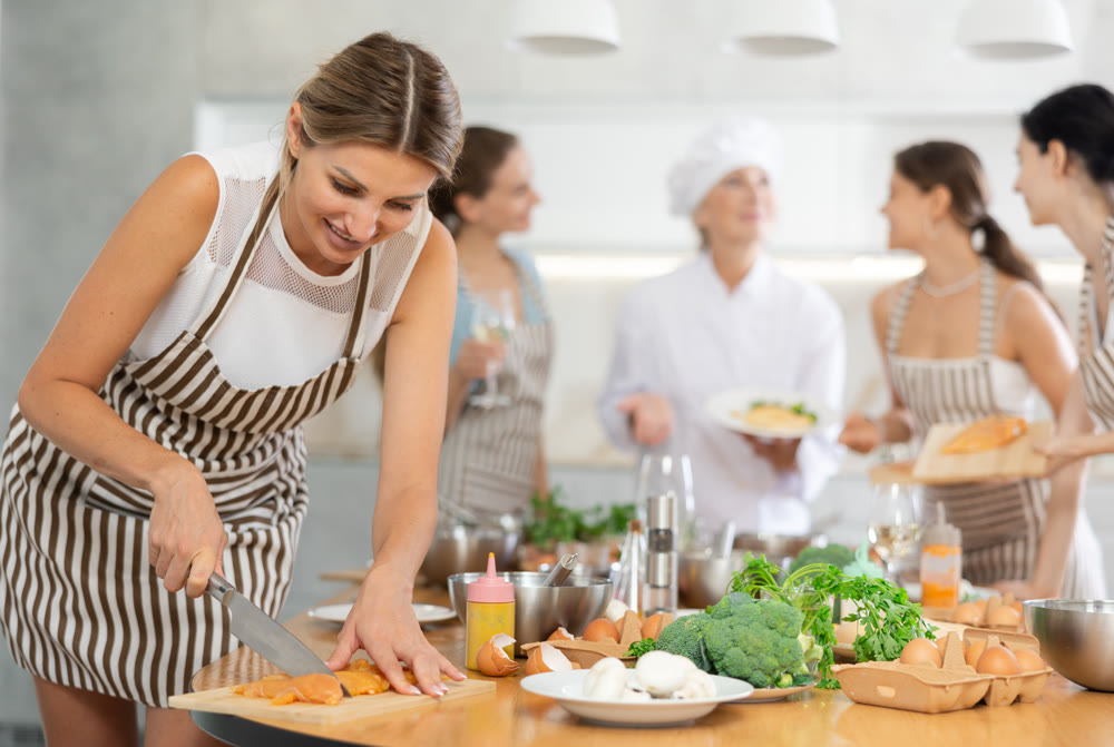 Young woman cutting raw chicken breast