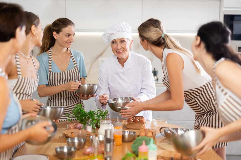 Elderly woman teaching cooking to group of woman