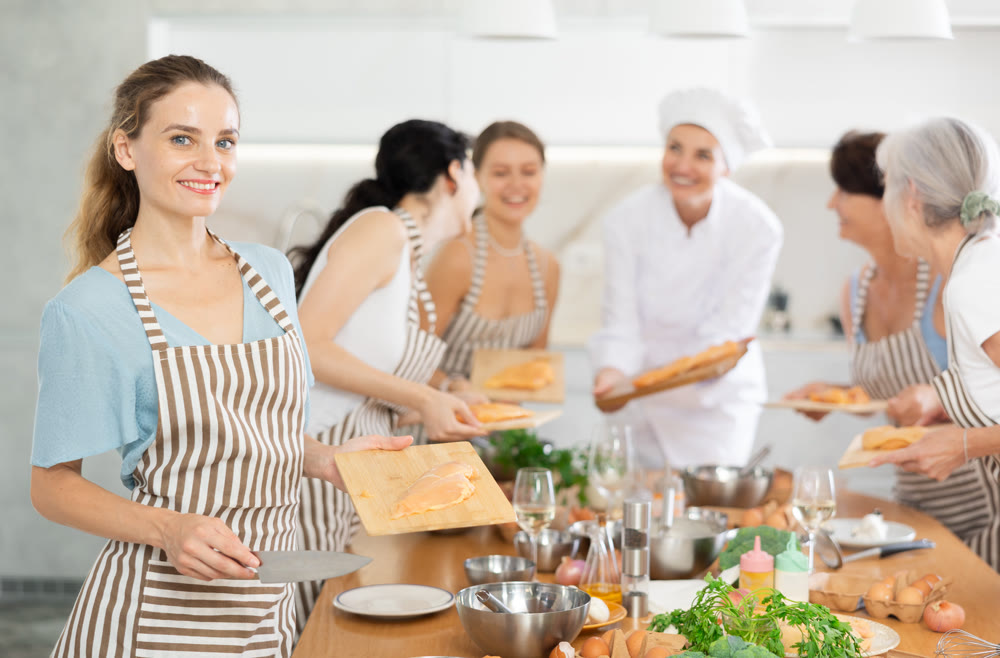 Young woman preparing chicken at master class