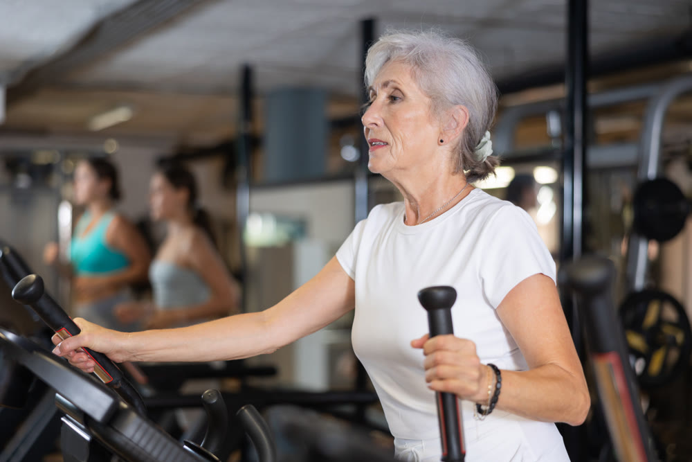 Elderly woman training on an elliptical machine