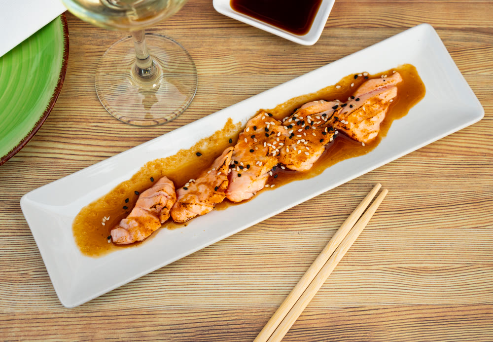 Sake tataki of salmon in sesame crust and soy sauce closeup