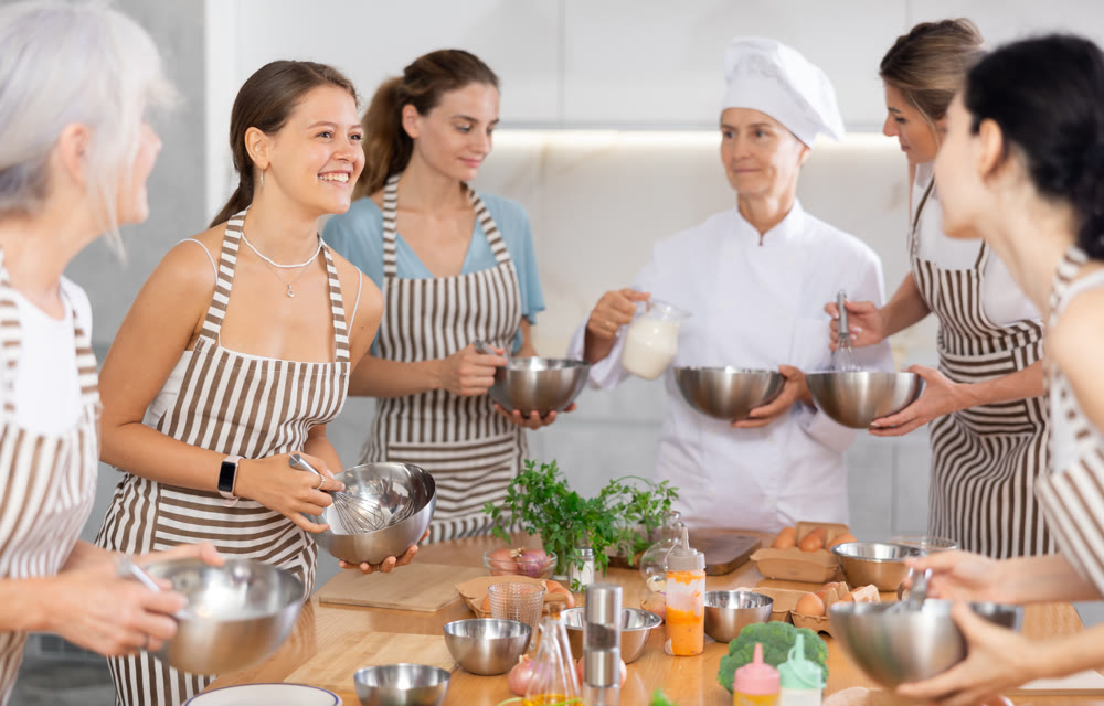 Young female visitor has nice conversation with person facing buddy vis-a-vis at culinary courses