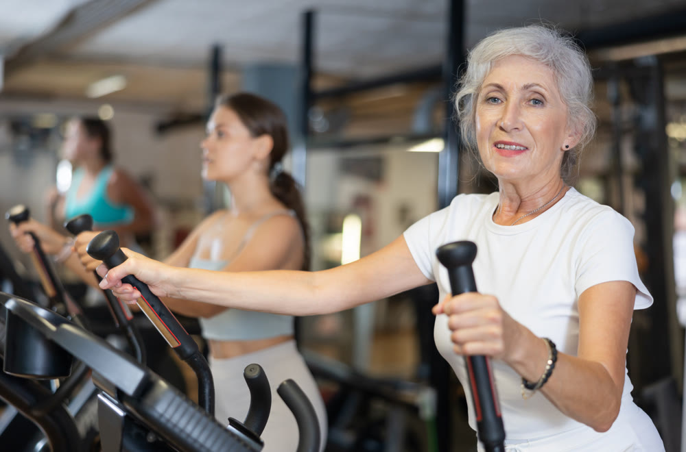 Elderly woman training on an elliptical machine