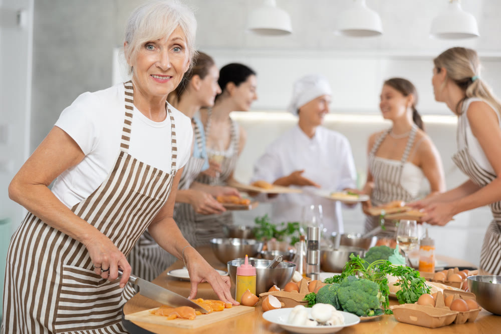 Mature woman cutting raw chicken