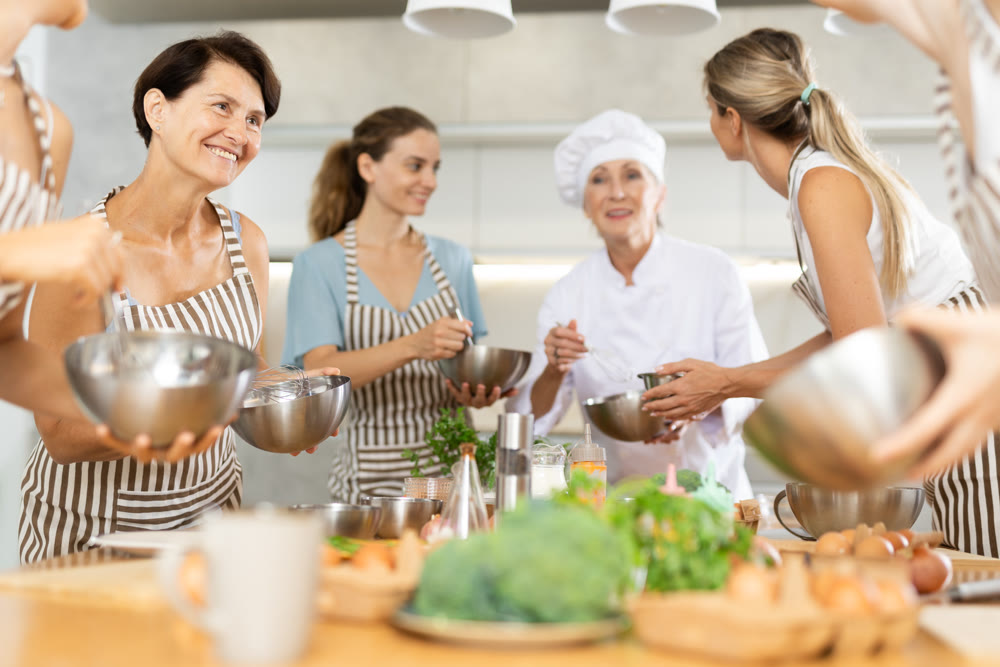 Elderly woman teaching cooking to group of woman
