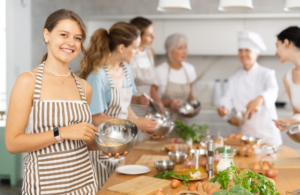 Girl while studying at culinary workshop, cooks appetizing sauce, marinade, dough in bowl.