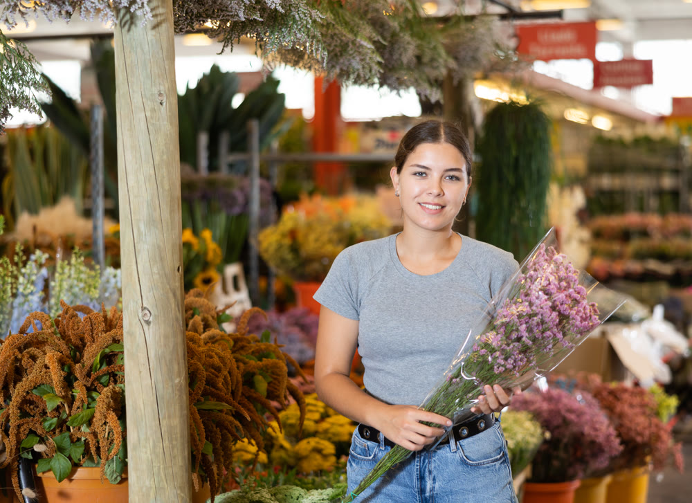 Happy young woman choosing colorful bouquet in flower shop