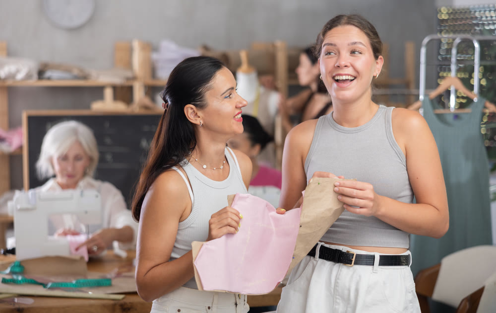 Young and middle-aged women holding textile detail fixed on paper