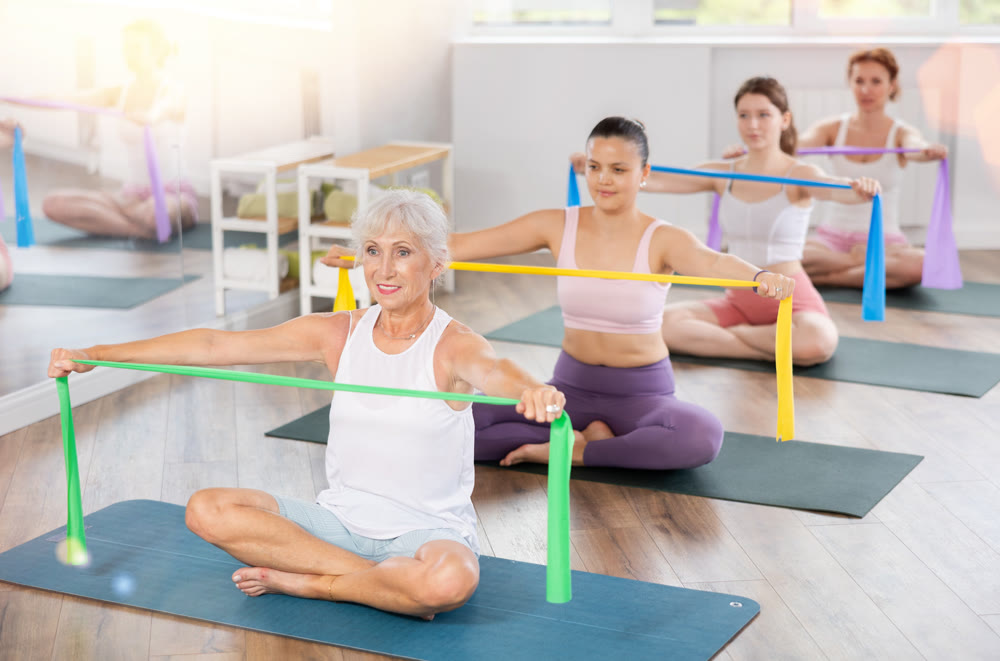 Senior lady performing exercises with resistance band in pilates class