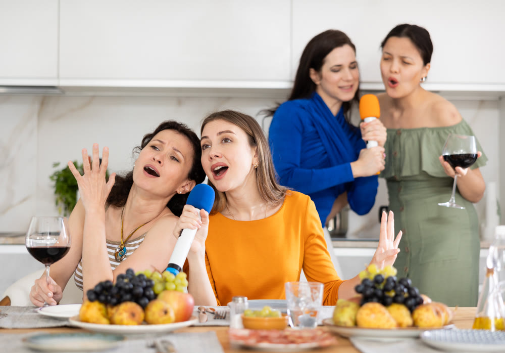 Happy smiling women celebrating friendship, birthday or festive season singing at home