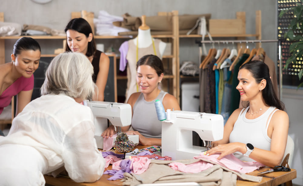 Group of women sew and draw pattern at sewing workshop