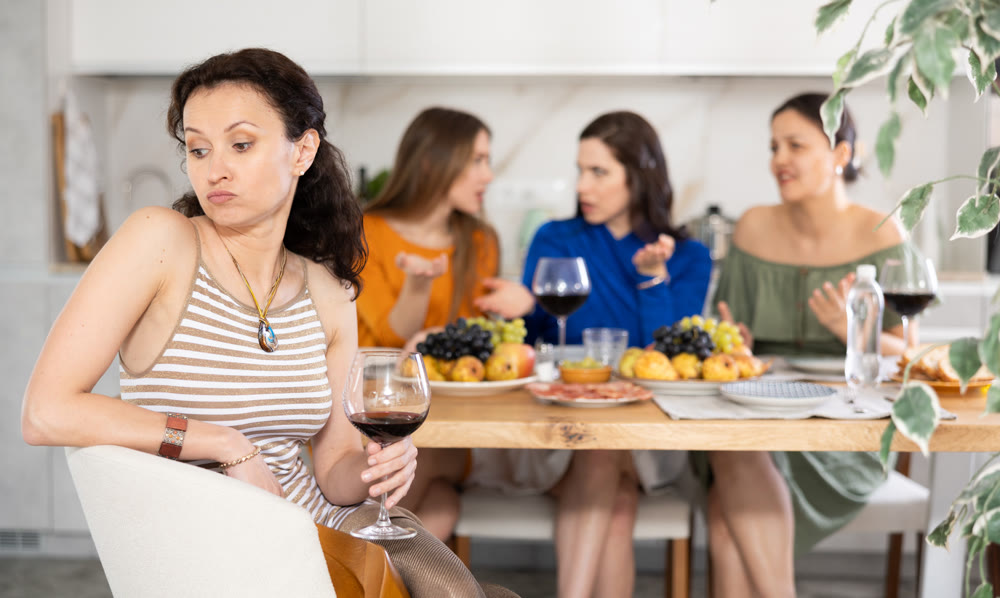 Upset woman listening to criticism from friends during home gathering